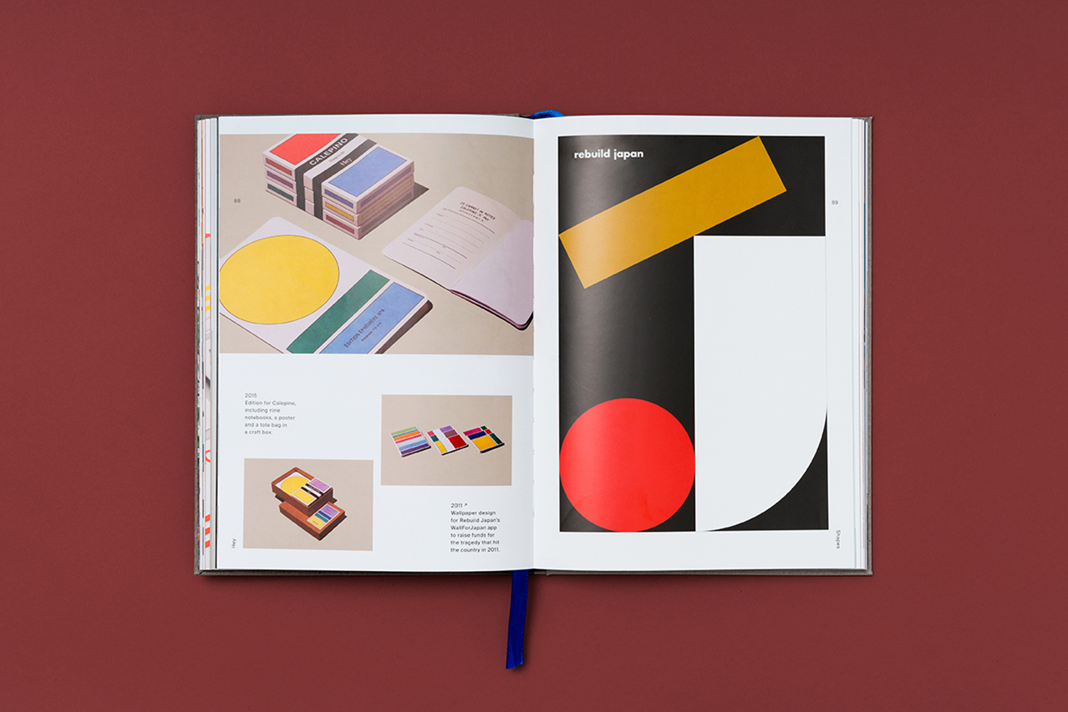 Open book featuring graphic design layouts with geometric shapes, vibrant colors, and minimalist typography, set against a deep red backdrop.