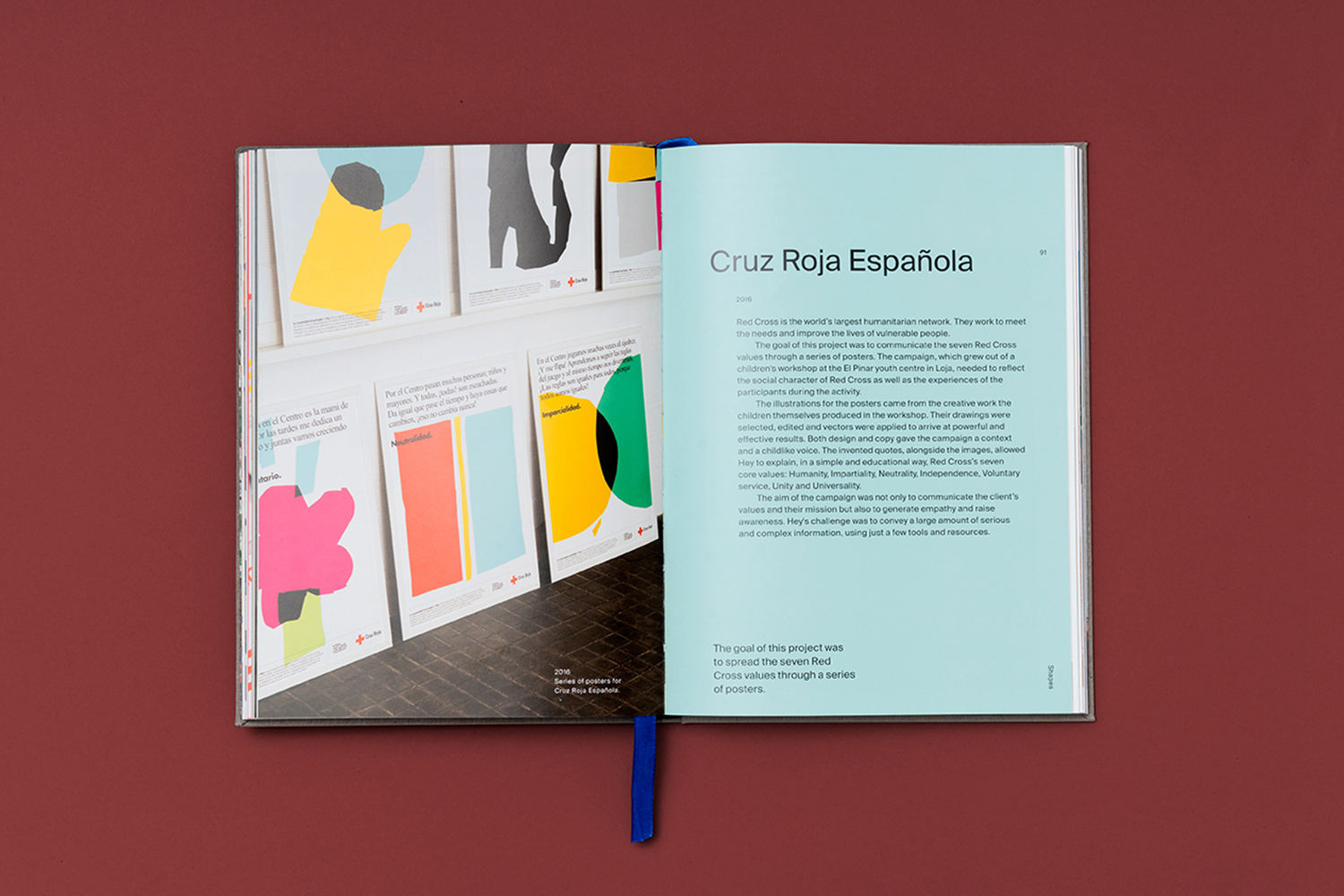 Open book featuring a series of abstract posters with geometric shapes and Red Cross logos, set against a colorful, light blue backdrop.