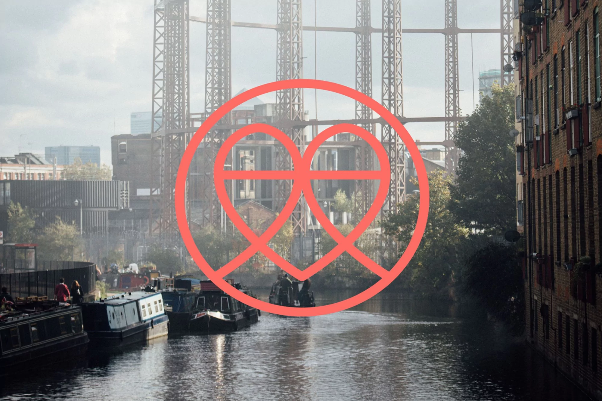 Urban river scene featuring boats on water with a red graphic overlay. Industrial buildings and architectural structures are visible in background.