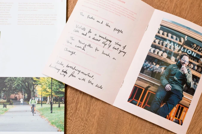 Close-up of a book on a wooden surface featuring a photograph of a man in front of a store and a cyclist on a path in a park.