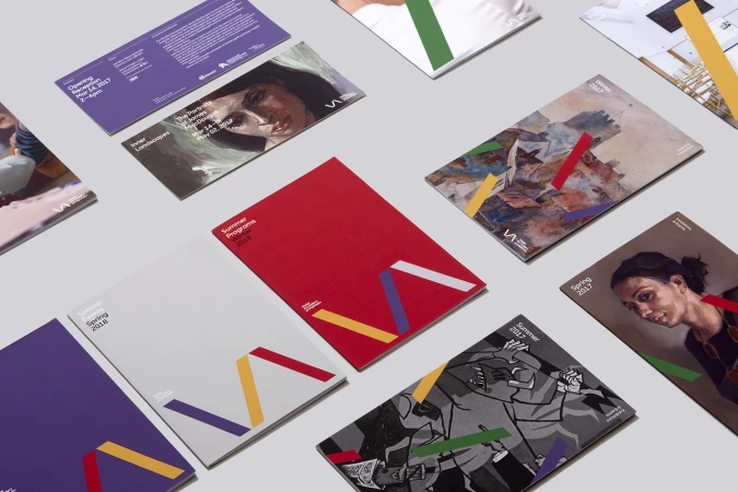 Arrangement of colorful event pamphlets and promotional materials featuring art and design imagery on a clean, neutral background.