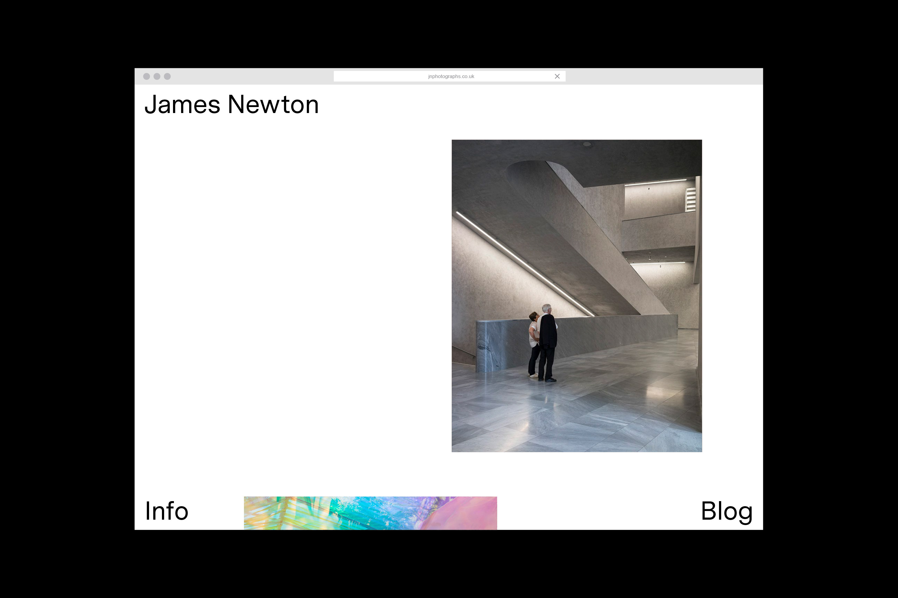 Two people stand inside a concrete-heavy modern interior featuring stairs and grey flooring, seen through a website display on a monitor.