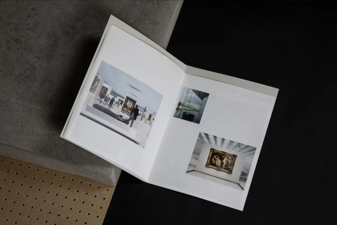 Open book displays photos of museum interiors and modern buildings, resting on grey and black surfaces, showcasing architectural photography.