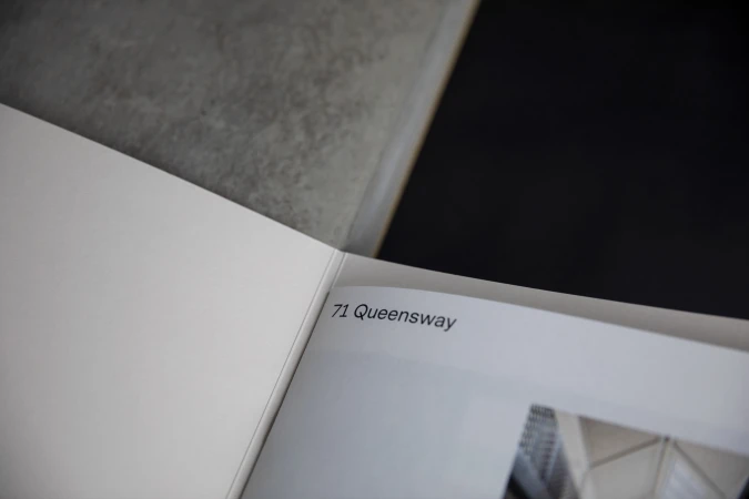 Open book featuring architectural photography and the text '71 Queensway', set against a modern grey and black background.