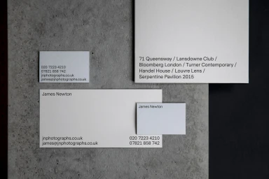 Minimalist corporate stationery items including business cards and letterheads arranged on textured grey concrete.