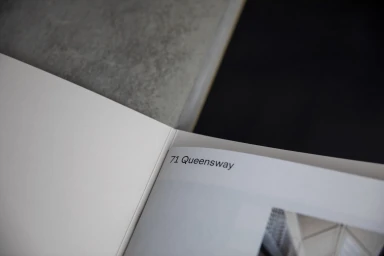 Open book page showing printed text 71 Queensway resting on a textured grey surface