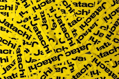 Overlapping yellow stickers with bold black Jatachi branding scattered across a flat surface.