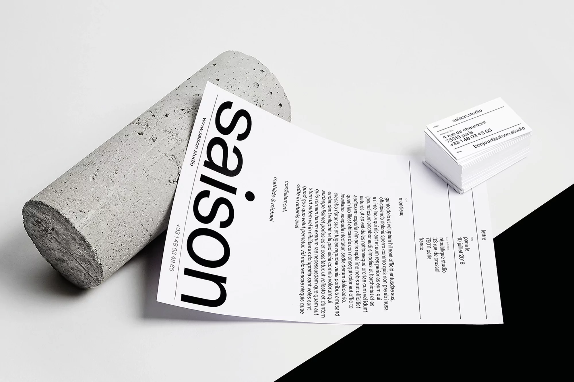 Stationery set featuring business cards, a letter, and a concrete block. The branding uses a clean, minimalist typography.
