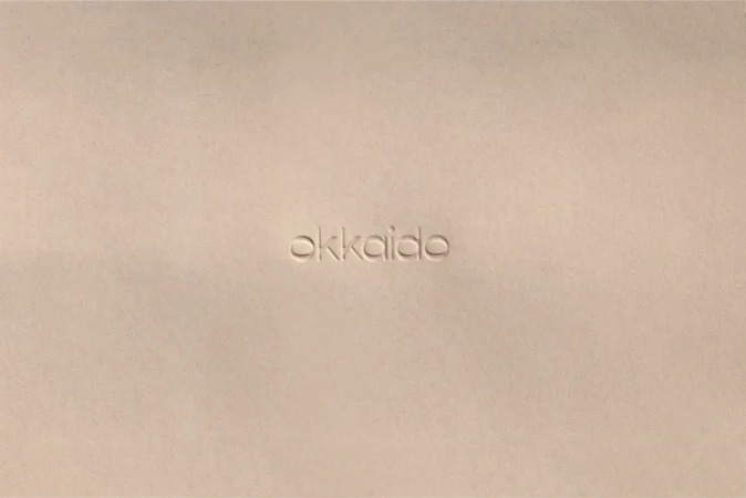 Cream colored surface features an embossed text that reads 'okkaido'. The background and text share the same colour, creating a subtle effect.