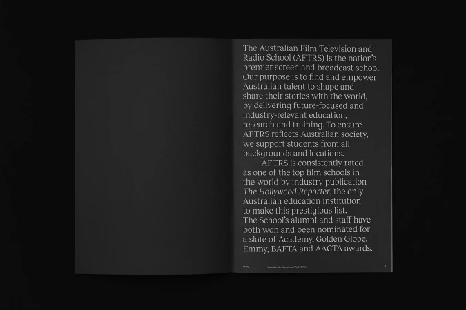 An open book on a dark surface shows text about the Australian Film Television and Radio School (AFTRS), a broadcast institution.