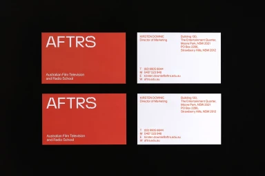 Two sets of business cards featuring red and white designs for AFTRS brand identity on a black surface