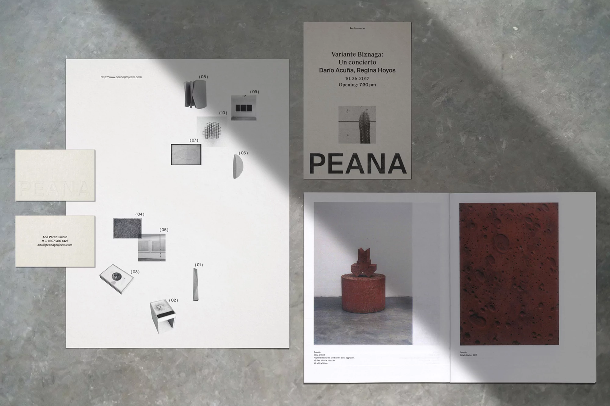 An art exhibition featuring posters and art books with minimalist design, clean typography, and shadow play on a light concrete background.