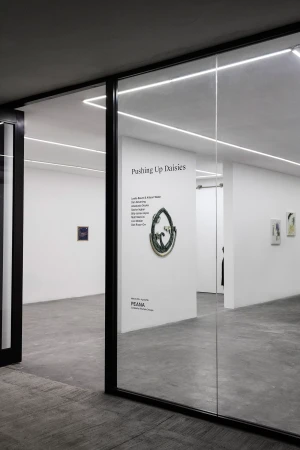 Art gallery exhibition featuring art pieces on display within a modern, minimalist space with white walls and glass door frames.