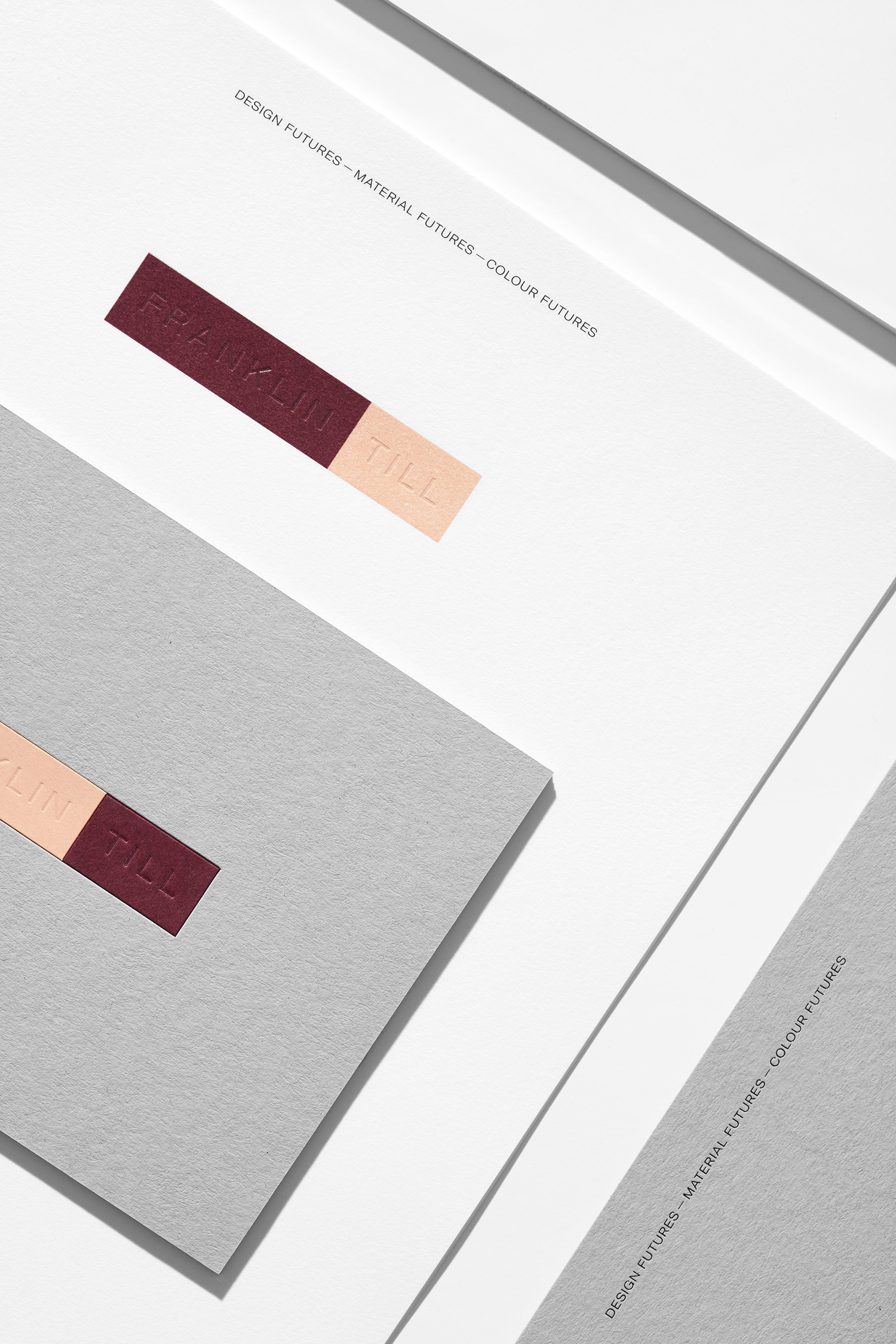 Rectangular color swatches on white and gray paper backgrounds, featuring embossed text and a minimalist design. Modern, flat lay.