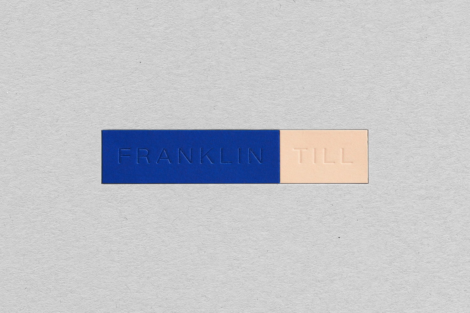 Close-up of a blue and cream colored embossed bar with the text 'FRANKLIN TILL' on a gray surface.
