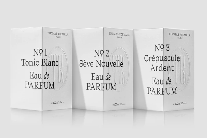 Three white Thomas Kosmala Paris Eau de Parfum boxes stand side-by-side with black text on a gradient gray reflective surface.
