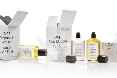 Thomas Kosmala perfume bottles and white packaging boxes arranged on a clean white seamless studio surface.