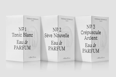 Three white Thomas Kosmala perfume boxes labeled Tonic Blanc, Seve Nouvelle, and Crepuscule Ardent against a pale grey backdrop