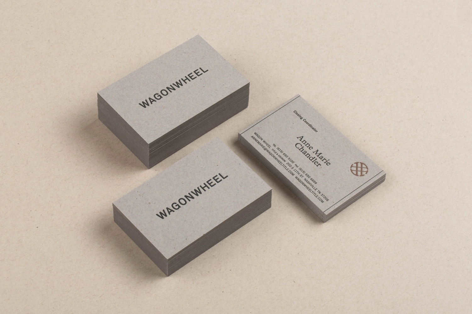 Three stacks of grey business cards with black typography placed on a textured beige paper background.
