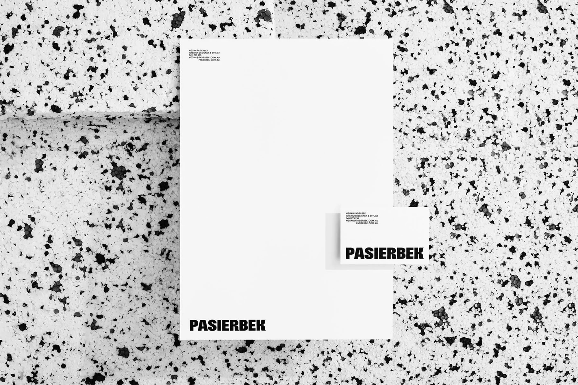 Stationery set featuring a letterhead and business card on a textured surface, showcasing minimalist design and professional branding.
