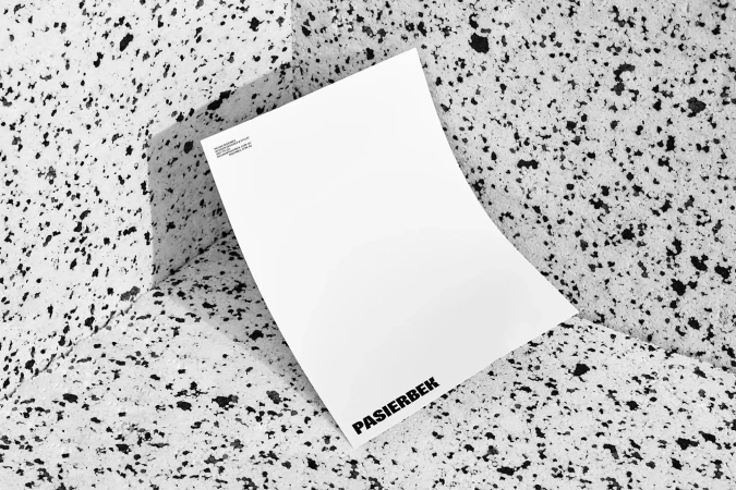 Minimalist studio shot of a white paper sheet with black text on a speckled black and white stone-like surface. Copy space is available.