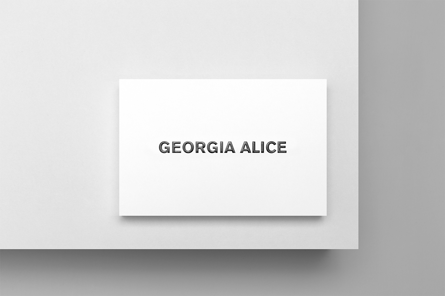 A close-up shot of a white card with the text 'Georgia Alice' on a white surface.