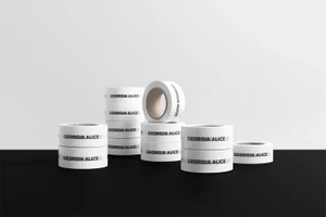 Stacks of branded white adhesive tape featuring Georgia Alice logo against a white and black background