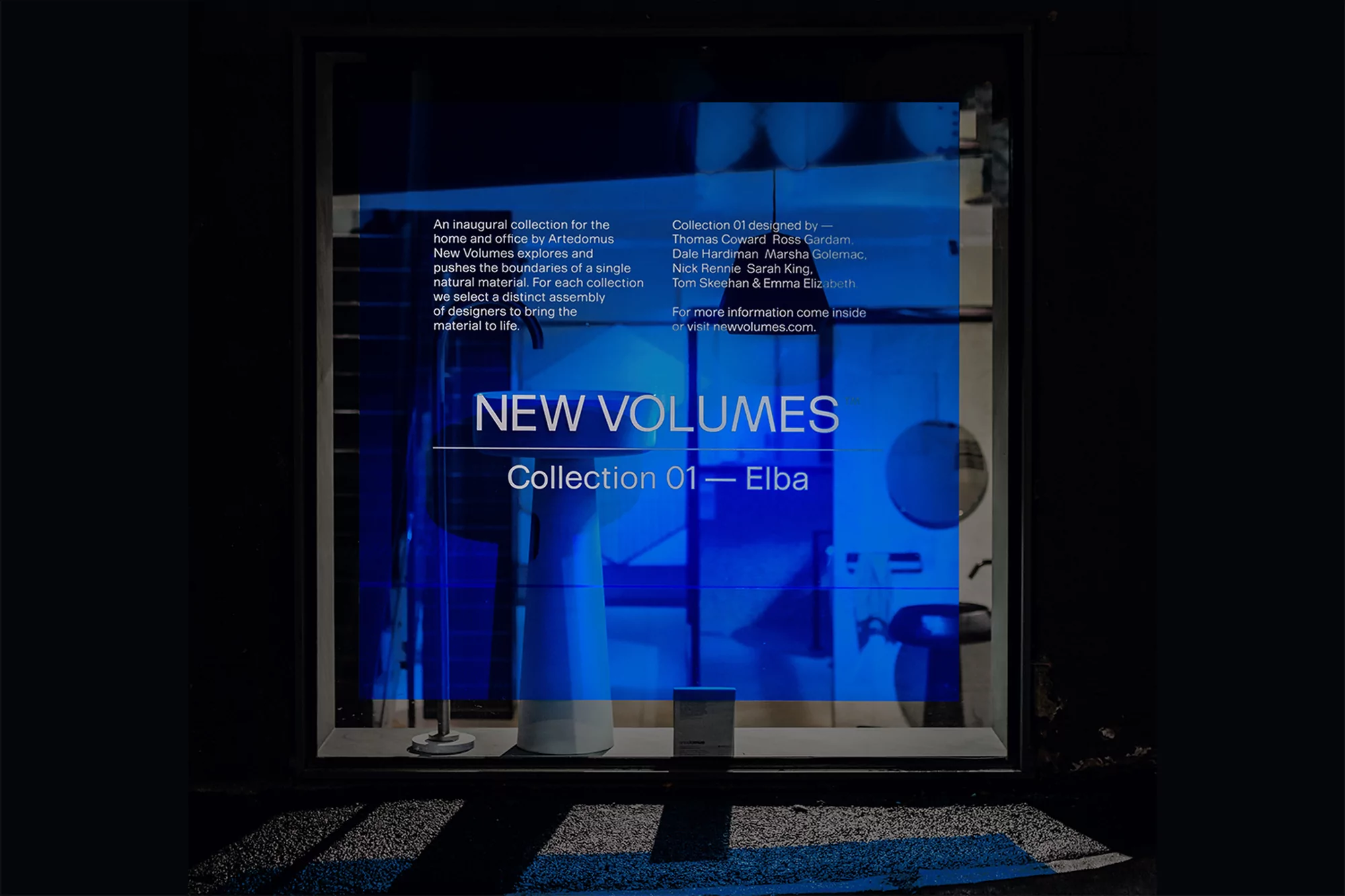 Artedomus New Volumes Collection 01 Elba display in a dark storefront featuring sinks and brand text in a blue hue and modern design.