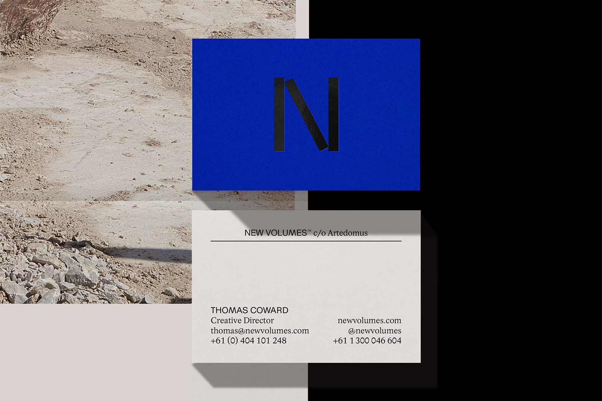 Two business cards, one with a blue background and a black 'N' and another white one with company and contact details against divided black/sand background.