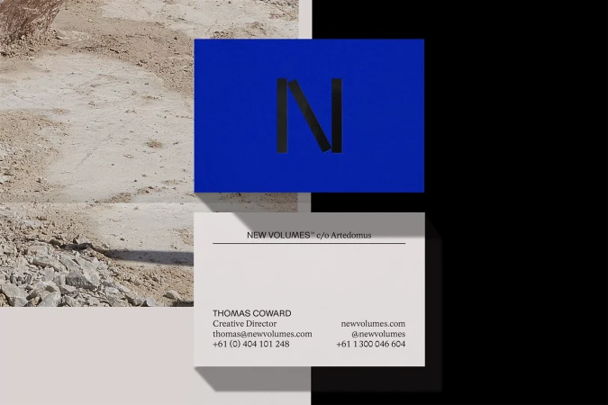 Two business cards, one with a blue background and a black 'N' and another white one with company and contact details against divided black/sand background.