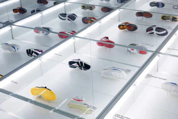 Array of colorful vintage athletic shoes displayed in illuminated glass display cases. Shoes are individually presented with labels.