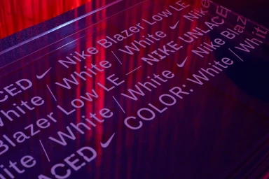 Transparent acrylic display block featuring engraved Nike product text and swoosh logos under red lighting.