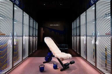 A furry weight bench and kettlebells inside a Nike retail space with perforated metal lockers.