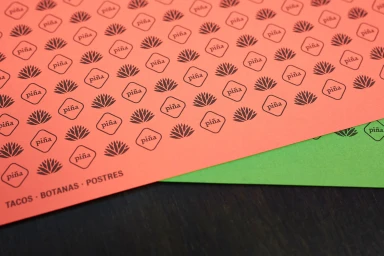Coral red patterned paper with repeating agave plant illustrations and text reading piña and TACOS BOTANAS POSTRES