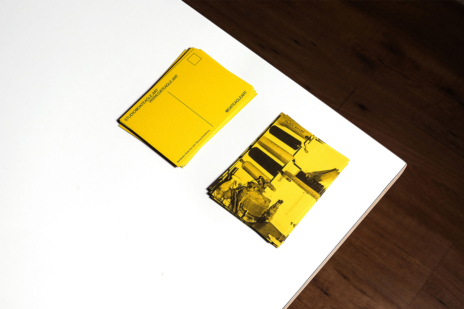 Two stacks of yellow postcards on a white surface, one featuring black abstract illustrations, contrasted by a dark wood background.