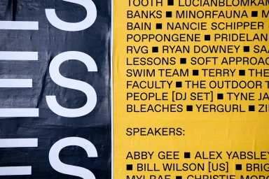 Close-up of a typography poster featuring bold white letters on black and artist names listed on yellow background