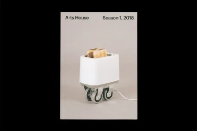 White toaster equipped with caster wheels containing two toasted slices of bread on a grey backdrop