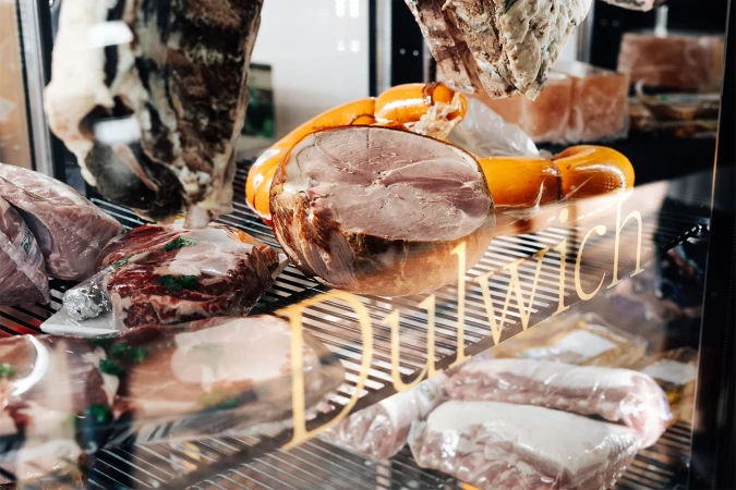Deli display case featuring cured meats and sausages, food presentation, indoor environment, commercial setting, food photography.