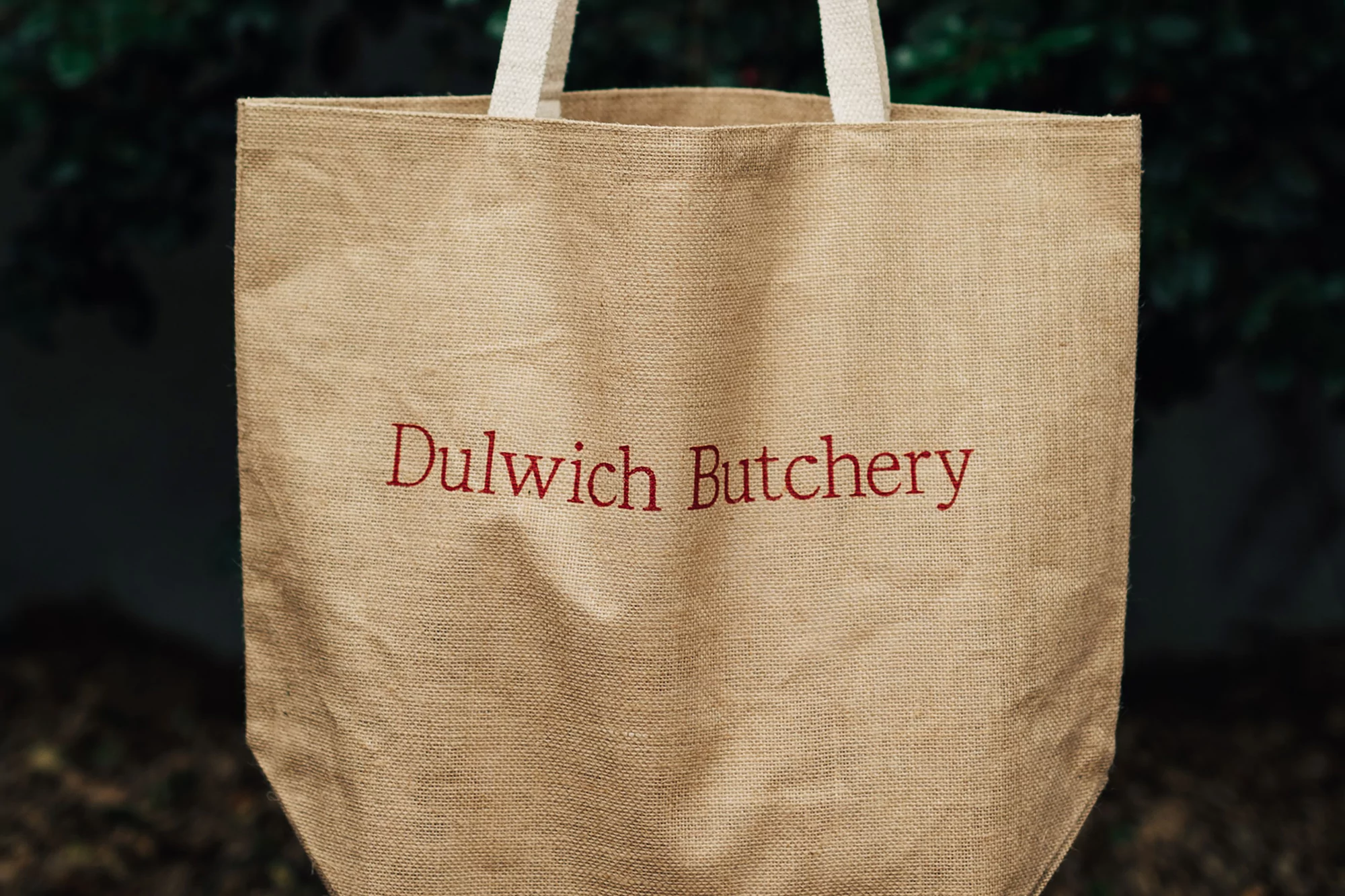 Jute tote bag with Dulwich Butchery logo against a blurred outdoor background showcasing sustainable and eco-friendly design.