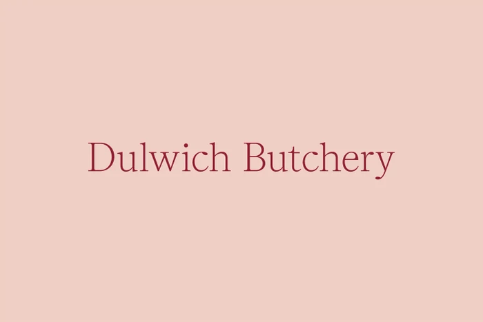 Minimalist brand identity graphic for Dulwich Butchery featuring red serif typography centered on a solid light pink background.