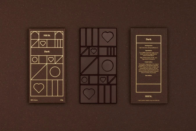 Three dark chocolate bars: one whole with a geometric design, plus front and back of a package with chocolate bar details.