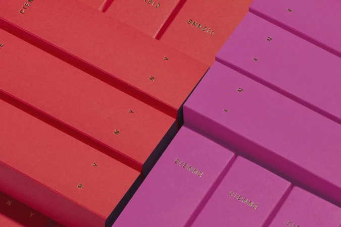 Arrangement of red and pink 'CIENNE' boxes. Repetitive pattern and minimalist studio product photography. The boxes create a geometric composition.
