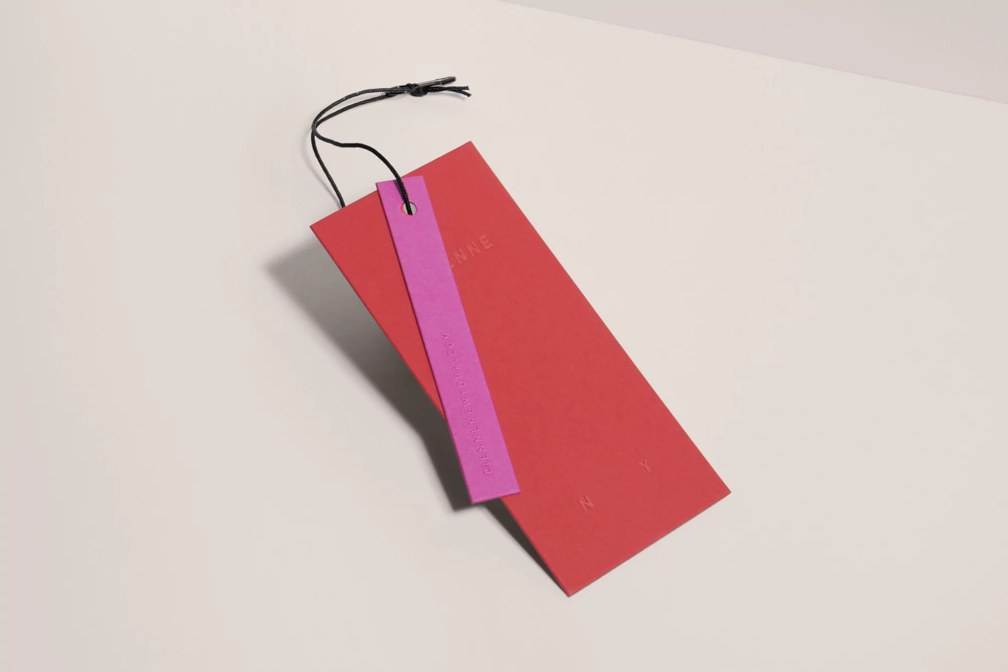 Red and pink tags with black string on a white surface, branding, simple product photography for fashion and retail concept.