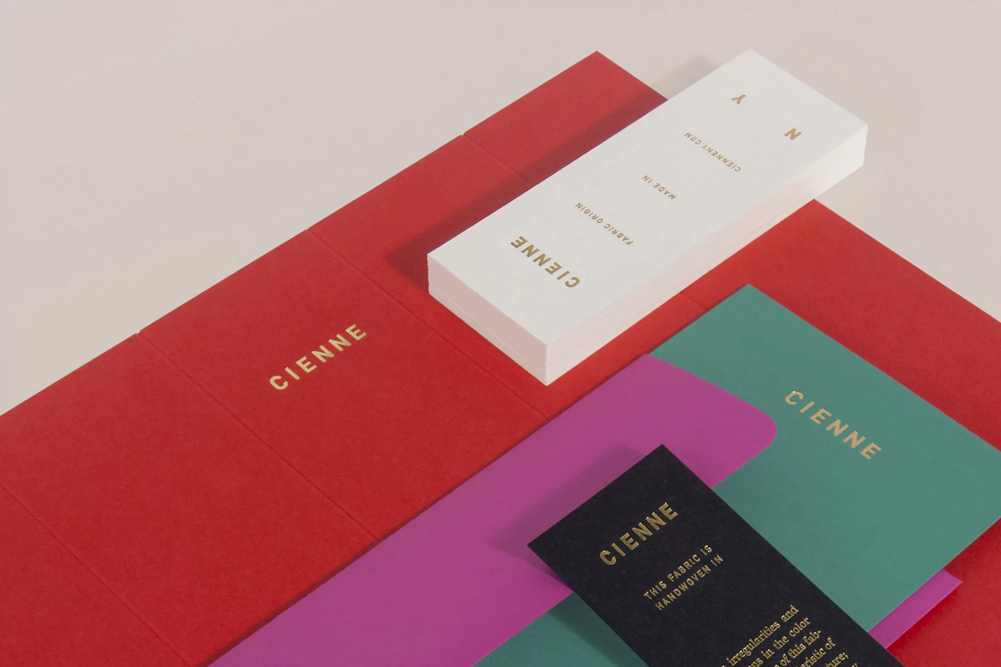 Promotional product shot of Cienne brand stationery including a red card, business cards, and a black fabric sample.