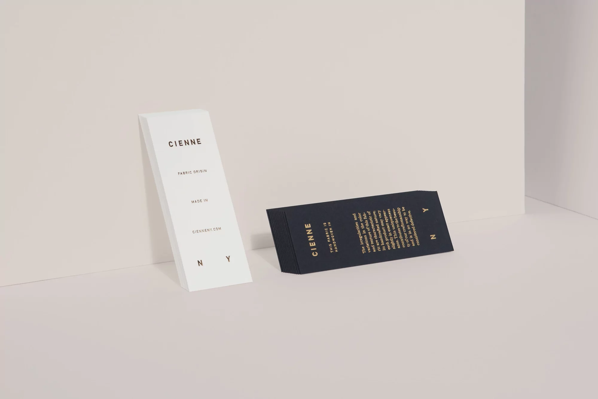 Cienne brand identity tags leaning against a minimal neutral studio background