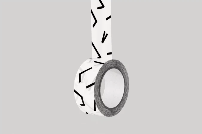 Roll of white patterned tape hanging down. The tape has black geometric designs. The backdrop is a solid pale gray color.