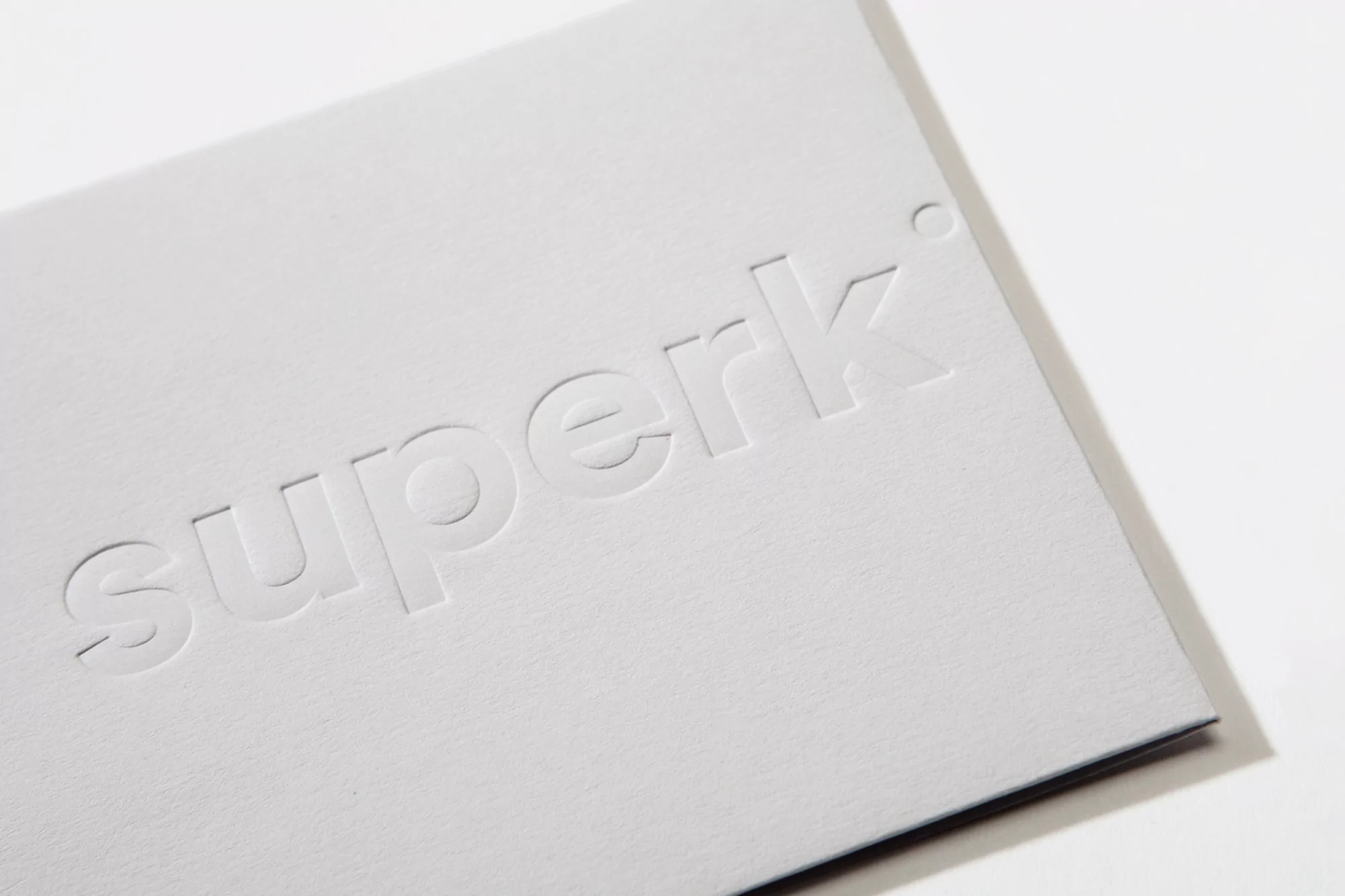 Embossed 'superk' logo on a white card, presenting a clean and minimalist design, promoting the brand's identity and image.
