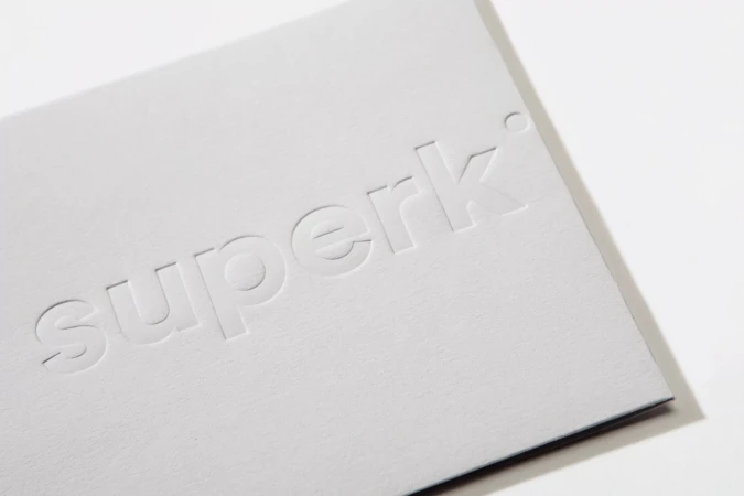 Embossed 'superk' logo on a white card, presenting a clean and minimalist design, promoting the brand's identity and image.