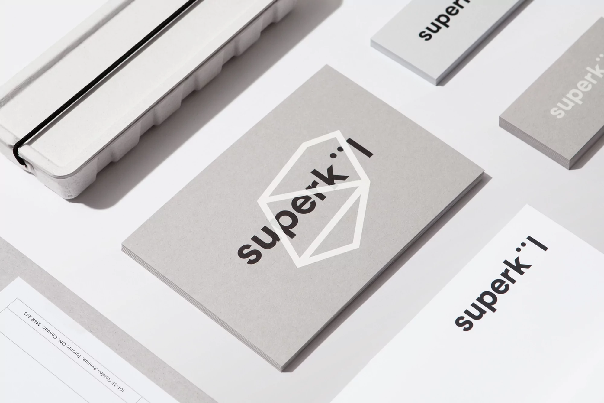 Promotional material featuring Superk'l brand on business cards and packaging, set against a clean, bright studio background.