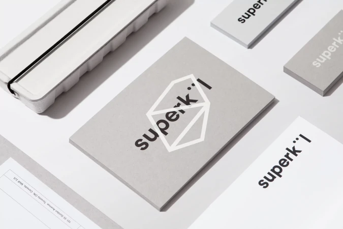 Minimalist stationery layout displaying the SuperKul brand identity with grey cards and white paper on a white surface.